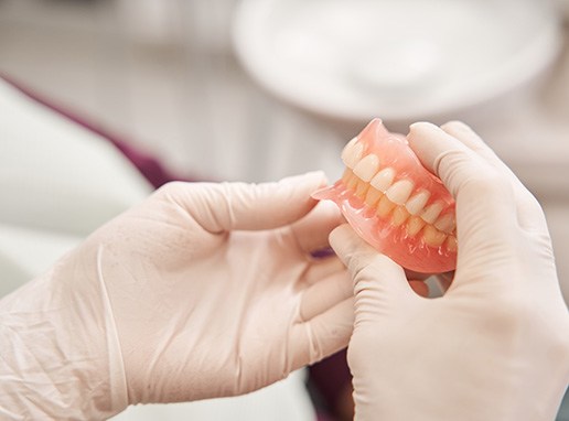 Gloved hands holding complete set of dentures
