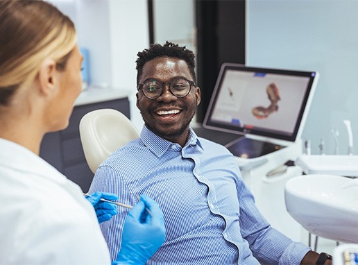 Dentist talking to smiling patient in treatment chair