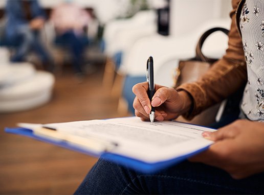 Woman filling out dental insurance form in lobby